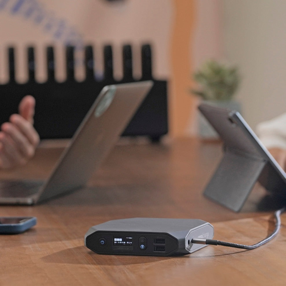 Omni power bank charging a tablet and laptop on a desk